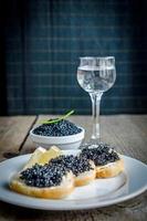 sándwiches con caviar negro y vaso de vodka