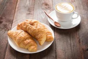 Fresh baked croissants and coffee on wood table photo