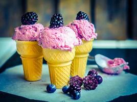 Ice -cream in cones with berries on rustic wooden background
