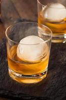 whisky bourbon con una esfera de cubitos de hielo foto