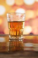 glass of rum whiskey over defocused lights background photo