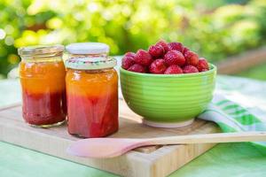 mermelada de fresa casera en diferentes frascos y fresas maduras frescas foto