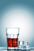 Glass of cola with ice cubes photo