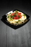 espaguetis a la boloñesa en placa negra foto