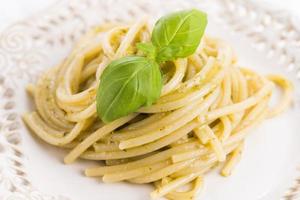 espagueti de pasta italiana con salsa de pesto y hojas de albahaca foto