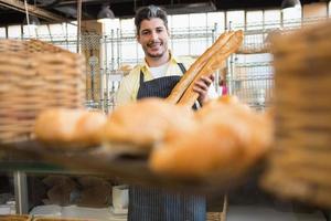 Cheerful waiter holding two baguettes photo