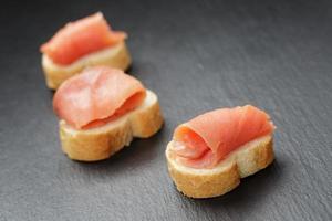baguette slices with curred salmon on slate background