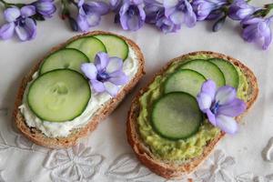 Green sourdough open face sandwiches with purple edible flowers