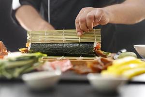 maestro de sushi prepara futomaki foto
