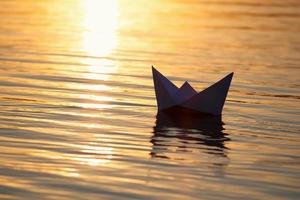 Paper boat sailing on water with waves  and ripples