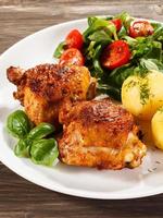 Roasted chicken legs, boiled potatoes and vegetables photo