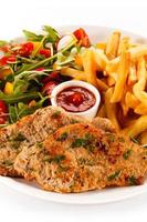 Fried steaks, French fries and vegetables photo