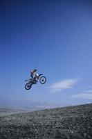 ciclista de montaña saltando contra el cielo azul foto