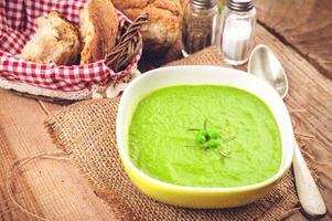 sopa de guisantes verdes en un tazón con pan y crema agria foto