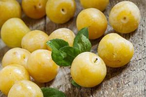 Ripe yellow plums on old wooden background