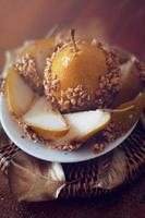 Caramelized pear dipped with peanuts decorated with golden leaves