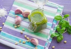 Green pesto in a glass jar and ingredients