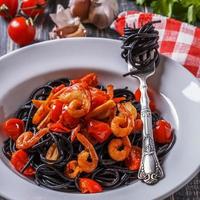 Black spaghetti with prawns and tomato.