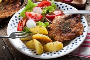 Grilled meat with salad and roasted potatoes. photo