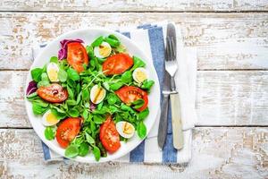 Ensalada verde fresca con lechuga de cordero, tomates y huevos de codorniz foto