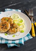 chicken cutlets with lemon and herbs on a white plate photo