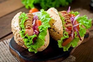 Hotdog with ketchup mustard and lettuce on wooden background.