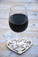 glass of red wine with heart decoration photo
