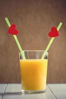 Orange juice glass with red hearts as a kissing lips photo