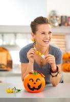 Woman eating trick or treat candy in halloween decorated kitchen