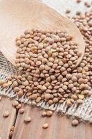 Organic lentils with wooden false on burlap background photo