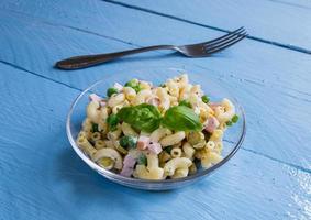 Pasta salad in a glass bowl on blue wood