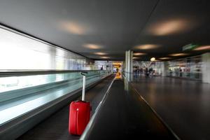 blurred moving escalator with red trolley in airport photo