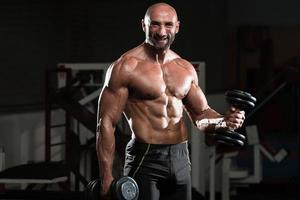 hombre sano trabajando bíceps en un club de salud foto
