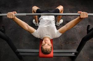 young man doing bench press workout in gym photo