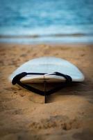 tabla de surf con correa en la arena, mar de fondo