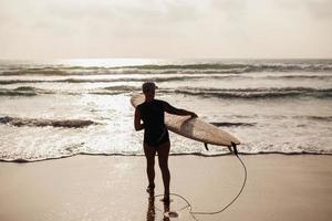mujer surf con vista trasera de la tabla de surf foto
