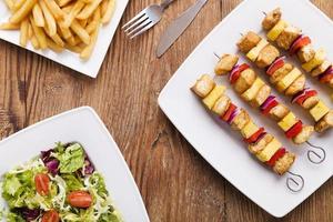 Grilled chicken skewers with pineapple, peppers and onions serve