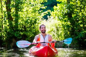 Hombre remando con kayak en el río para practicar deportes acuáticos
