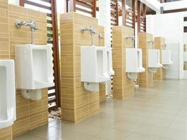 fila de urinarios en un baño público foto