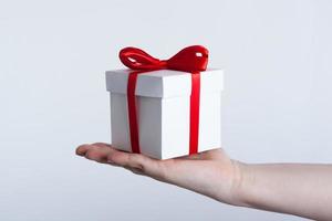 white gift box with red ribbon in hand photo