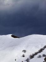 Off-piste slope and overcast gray sky in windy day photo