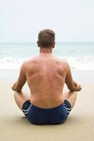 man meditating on beach. photo