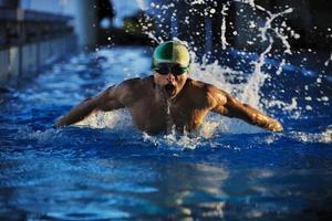 Un nadador con gorra y gafas saliendo del agua foto