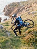 Ciclista llevando su bicicleta por la costa gallega. foto