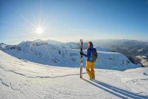 Esquiador contemplando la vista del atardecer desde la cima de la montaña nevada foto