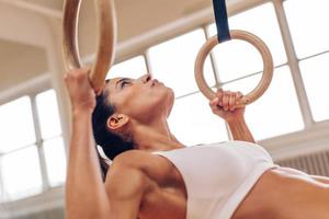 Strong woman doing pull-ups with gymnastic rings