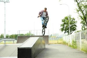 Young boy jumping with his BMX Bike at skate park photo