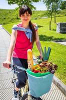 Young sportive woman with groceries in a basket bike