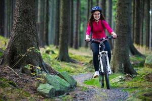 niña montando bicicleta en senderos del bosque foto