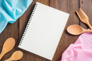 Recipe notebook, spoon, fork on wooden background